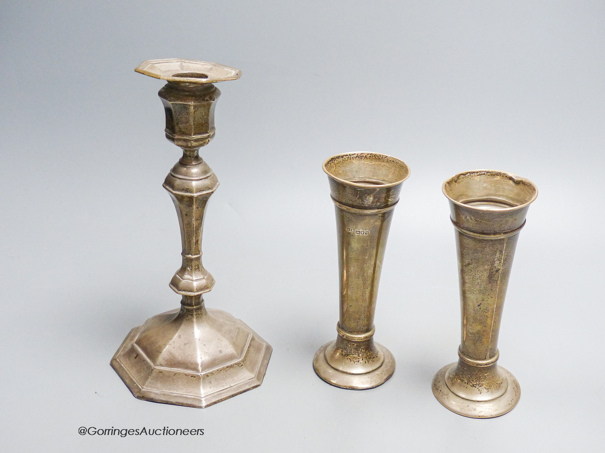 A George V silver mounted candlestick, William Hutton & Sons, Sheffield, 1912, height 20.5cm, weighted and a pair of silver posy vases, London, 1911, weighted.